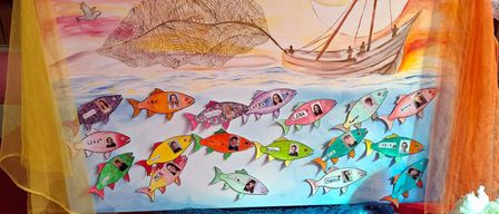 A colorful artwork with a boat catching fish, a sunset in the background, and a quote from Matthew 4:19. Each fish has a name.