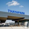 Eine Luftaufnahme des Eingangs zum Thaypark-Gebäude mit blauem Himmel und Wolken im Hintergrund. Das Gebäude hat ein blaues Schild mit den Worten Thaypark.
