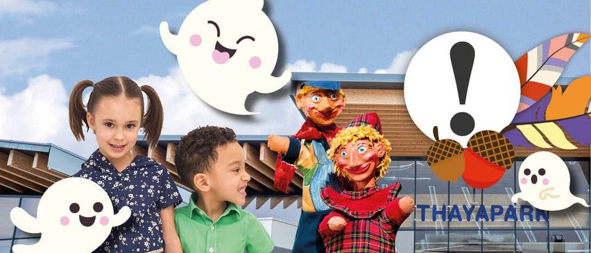 Zwei Kinder stehen neben einem Gebäude mit Puppen. Ein Geisterbild ist über ihnen, und ein Ausrufezeichen ist daneben.