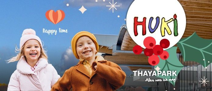 Zwei Kinder, ein Mädchen in Pink und ein Junge in Braun, lächeln vor einem Gebäude mit dem Wort 'HUKI' und einem Weihnachtsthema.