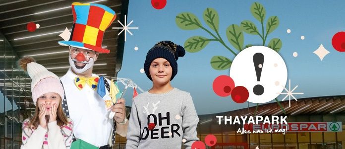 Eine Familie mit einem Clown und zwei Kindern in Winterkleidung steht vor einem Gebäude mit Weihnachtsdekoration.