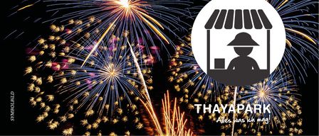 Ein lebhaftes Feuerwerk in der Nacht, mit explodierenden Feuerwerken am Himmel. Ein Schattenbild eines Verkäufers ist in einem Ladenschild abgebildet. Die Worte 'THAYAPARK' sind in großen Buchstaben am Boden geschrieben.