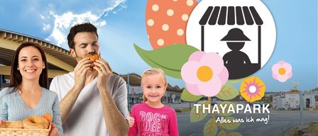 Ein Mann und ein Mädchen genießen eine Mahlzeit bei einer Outdoor-Veranstaltung, mit dekorativen Blumen und einem Marktstand im Hintergrund.