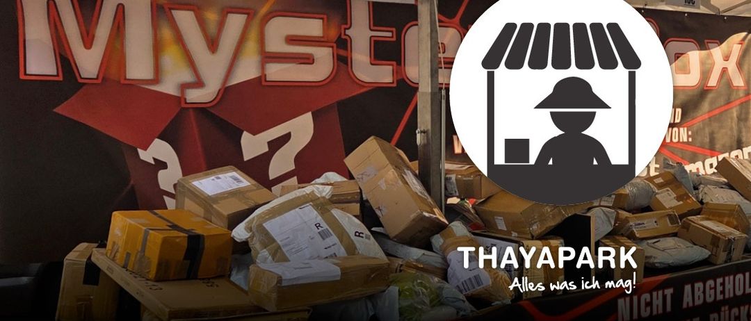 Ein Stapel verschiedener Pakete mit dem MyStore-Logo im Hintergrund und einer Silhouette einer Person. Der Text lautet 'THAYAPARK' und 'Alles was ich mag!'