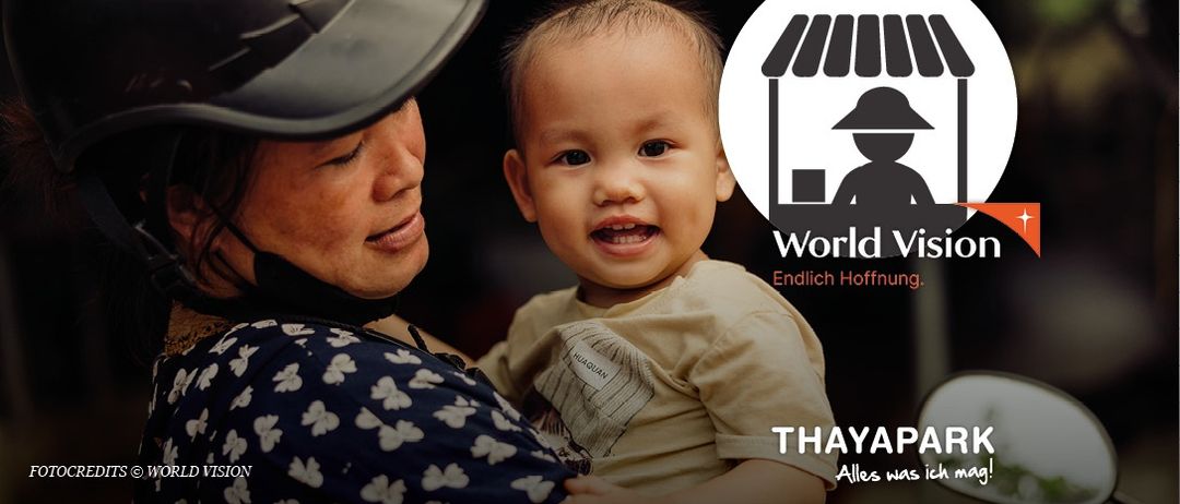 Eine Frau mit Hut und Gesichtsmaske hält ein lächelndes Baby in den Armen. Das Bild wird von World Vision gesponsert, mit einem Logo, das eine Person unter einem Hüttendach zeigt.