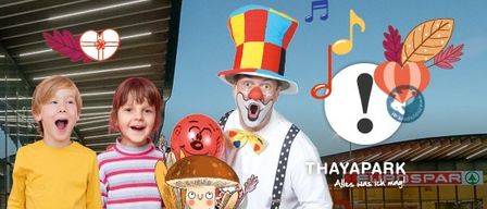 Three children and a clown with a colorful hat are standing in front of a building with musical notes and a heart in the background.