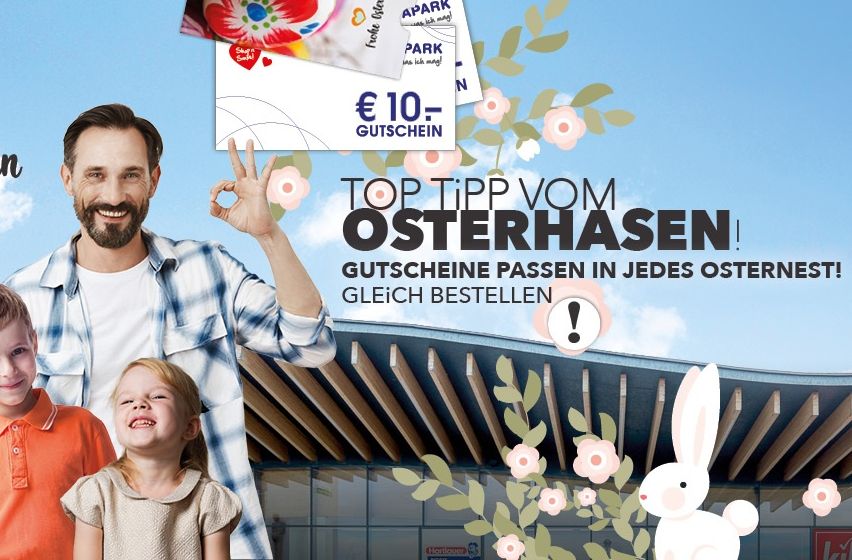 Eine Familie posiert für ein Bild mit einem Banner, das 'Top Tipp von Osterhasen' besagt. Der Mann zeigt den Friedenszeichen. Ostergeschenke sind im Einkaufszentrum erhältlich.