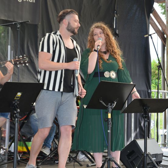 Bild enthält, Stage, Microphone, Adult, Male, Man, Person, Female, Woman, Concert, Shorts