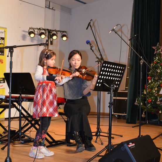Bild enthält, Person, Musical Instrument, Violin, Concert, Electrical Device, Microphone, Shoe, Stage, Group Performance, Face