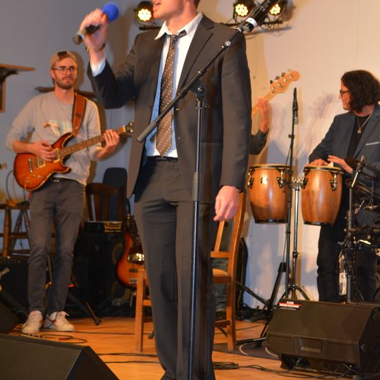 Bild enthält, Microphone, Group Performance, Music Band, Person, Concert, Adult, Male, Man, Guitar, Necklace