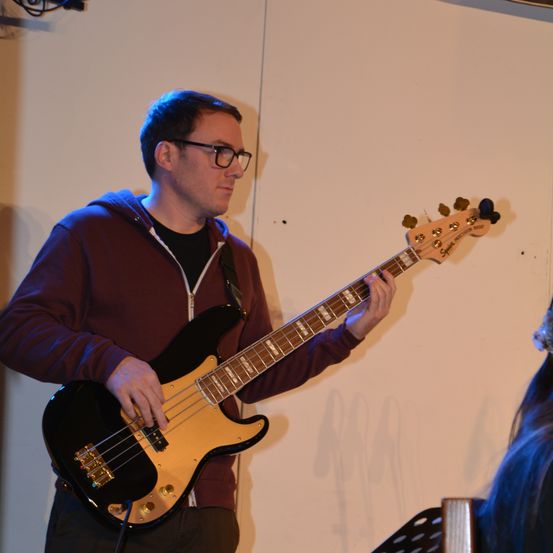 Bild enthält, Guitar, Musical Instrument, Electric Guitar, Adult, Male, Man, Person, Microphone, Bass Guitar, Glasses