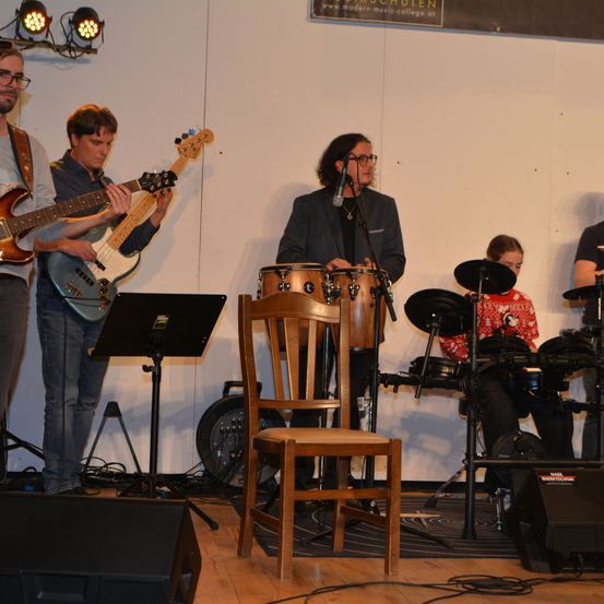 Bild enthält, Group Performance, Music Band, Person, Adult, Male, Man, Concert, Guitar, Chair, Glasses