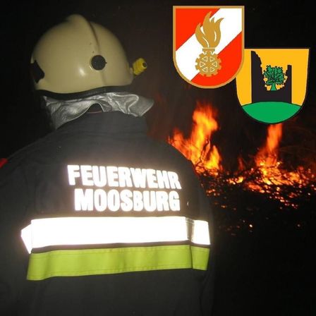 Ein Feuerwehrmann aus Moosburg steht neben einem brennenden Feuer mit Wappen im Hintergrund.