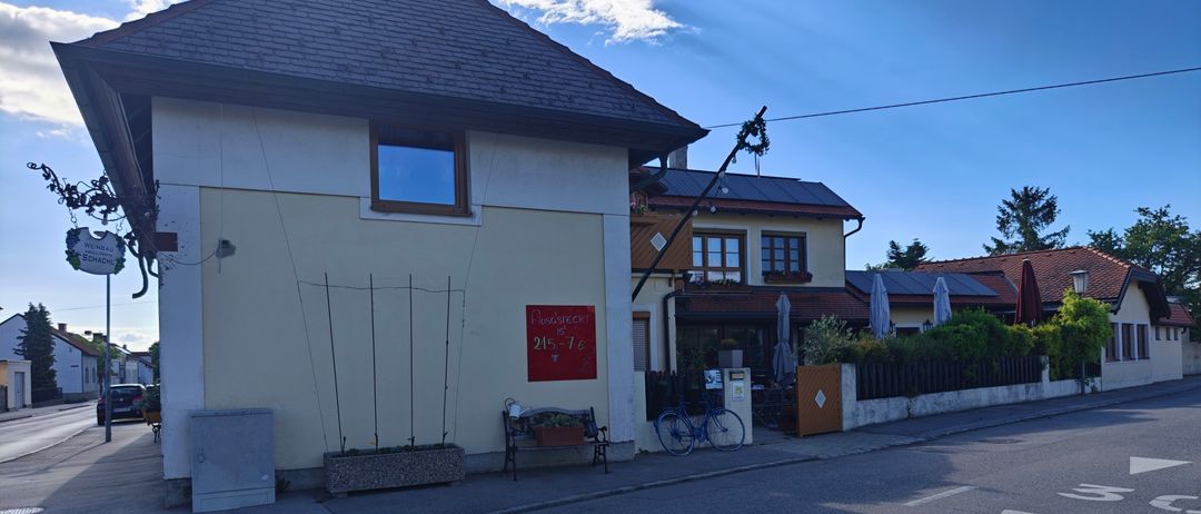 Ein Gebäude mit einem roten Schild und einer Bank auf dem Bürgersteig. Ein Fahrrad ist neben einem Mülleimer geparkt.