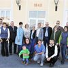 Eine Gruppe von Menschen in Geschäftskleidung steht vor einem Gebäude mit der Nummer 1843. Sie lächeln für ein Foto.