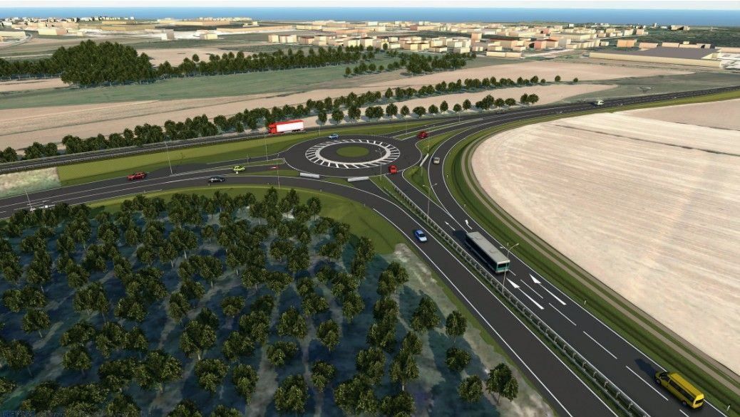Eine Autobahn mit mehreren Spuren und einem Kreisverkehr, umgeben von Bäumen und Gebäuden in der Ferne.