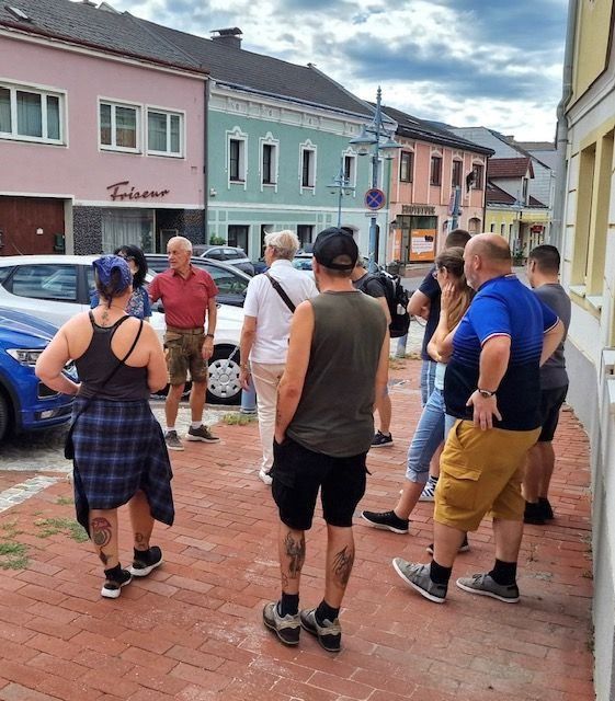 Touristen in Krems an der Donau stehen auf einem Gehsteig vor bunten Häusern.
