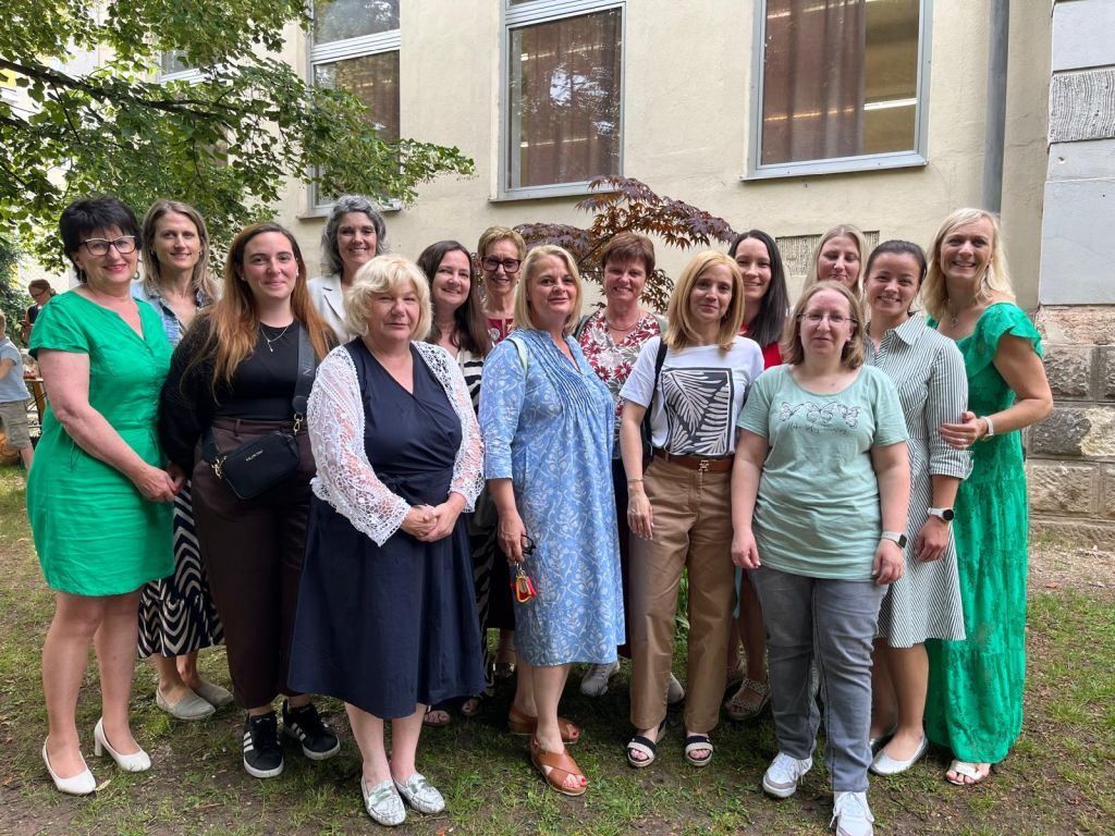 Eine Gruppe von Frauen in verschiedenen Outfits und Accessoires posiert für ein Foto vor einem Gebäude.