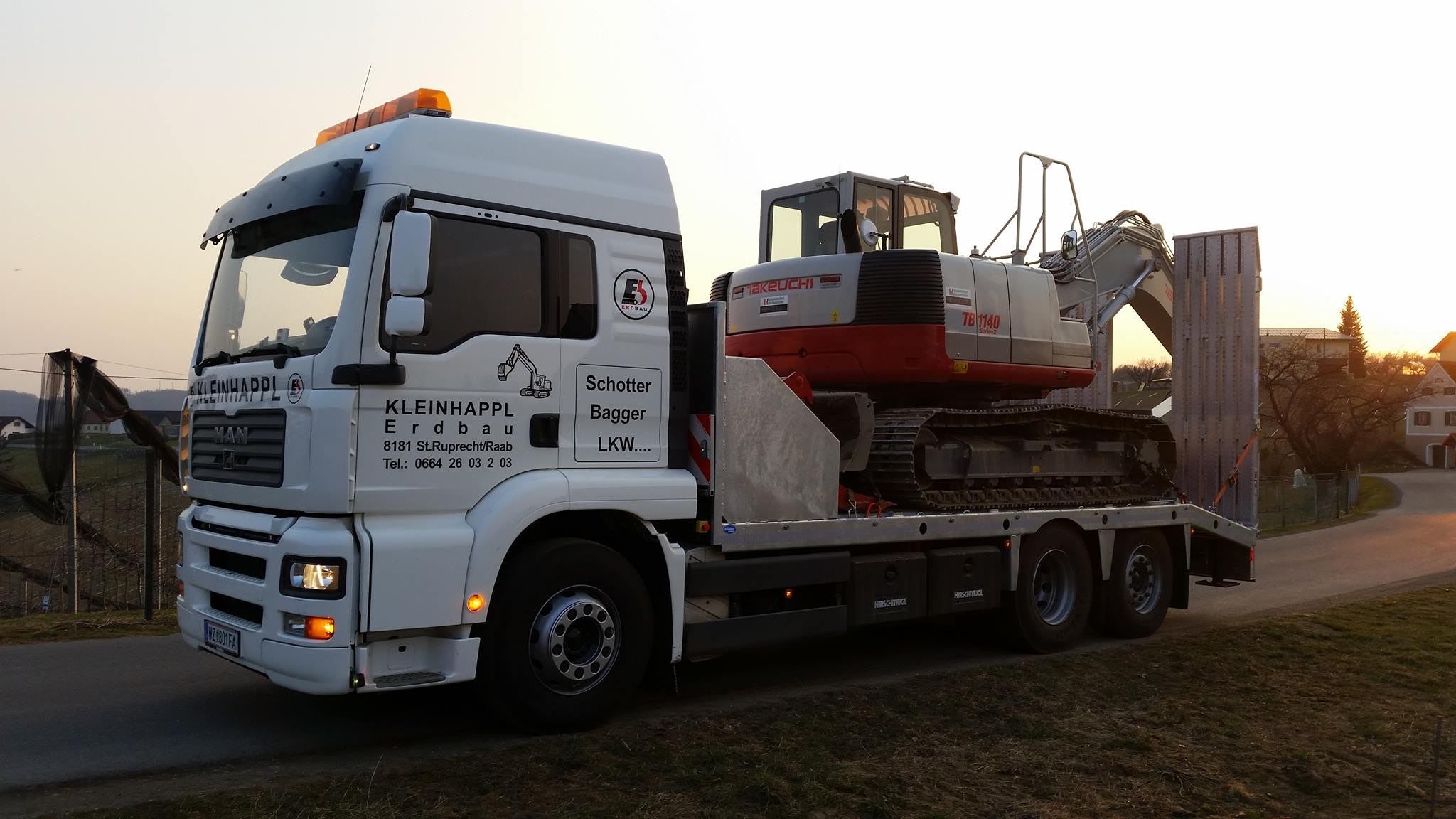Ein weißer Lkw mit einem Takeuchi-Bagger auf dem Anhänger. Der Lkw ist mit 'Kleinhappel Erdbau' beschriftet und zeigt Kontaktdaten.