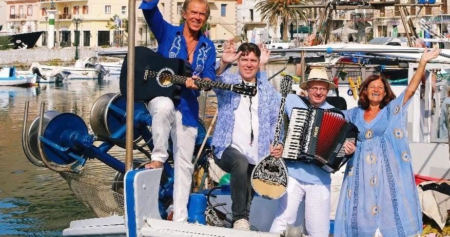 Drei Personen auf einem Boot. Ein Mann spielt Gitarre, ein anderer Mann spielt Akkordeon und eine Frau winkt. Ein Bootsmotor befindet sich auf dem Boot, und andere Boote und Gebäude sind im Hintergrund.