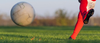 Ein junges Mädchen in einem roten Trikot tritt einen Fußball auf einem Rasenfeld. Das Bild enthält einen Bibelzitat, ein Datum und einen Ort für ein Fußballevent.