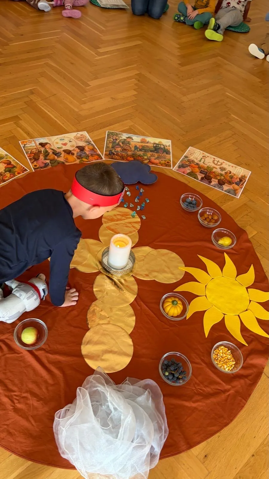 Ein Kind spielt mit einer Sonnenblumen-Aktivität auf einem Holzboden, umgeben von verschiedenen Lebensmitteln und Bildern.
