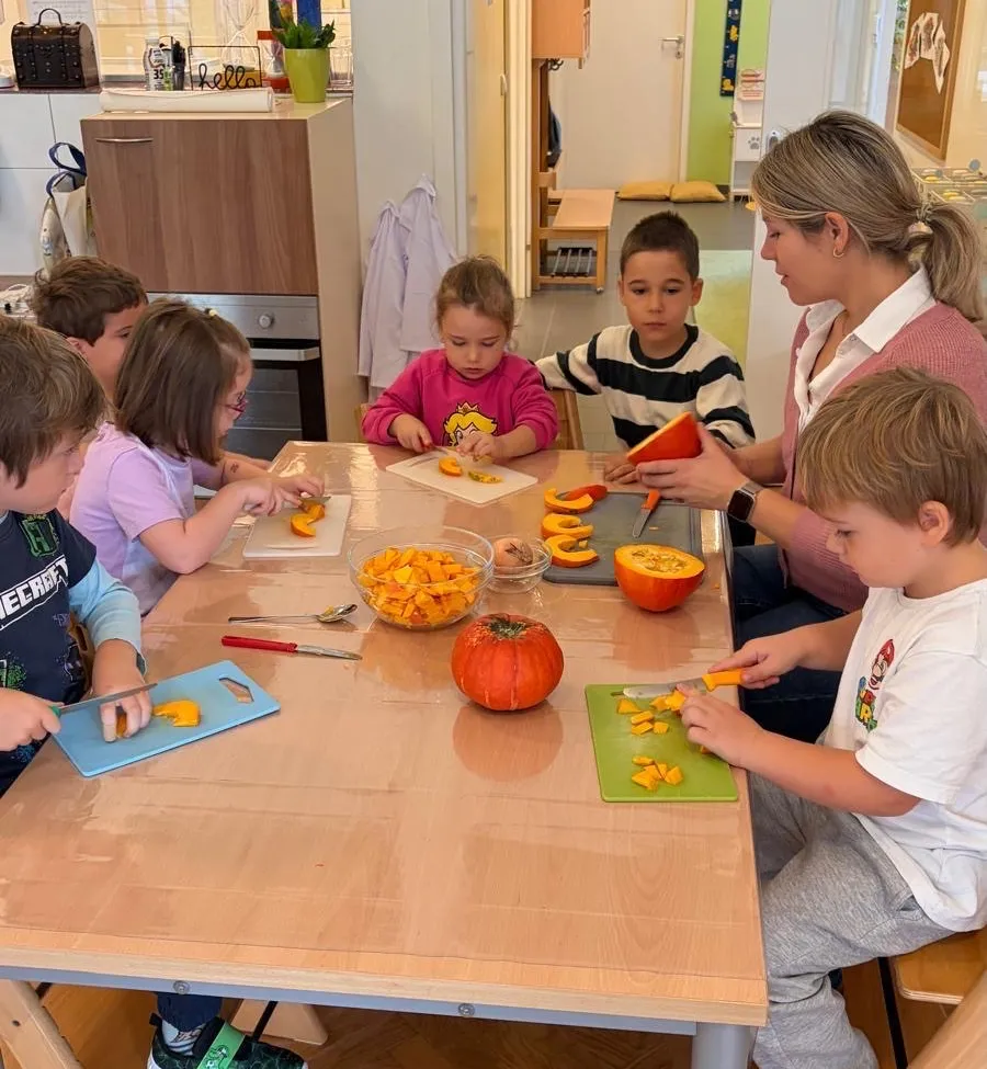 Eine Gruppe von Kindern und einem Erwachsenen sitzen um einen Tisch herum und schneiden Kürbisse.