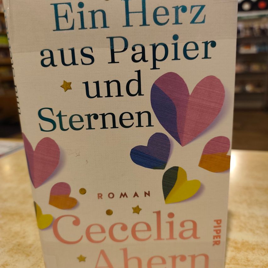Ein Buchcover mit dem Titel 'Ein Herz aus Papier und Sternen' von Cecelia Ahern, mit farbenfrohen Herzdesigns.