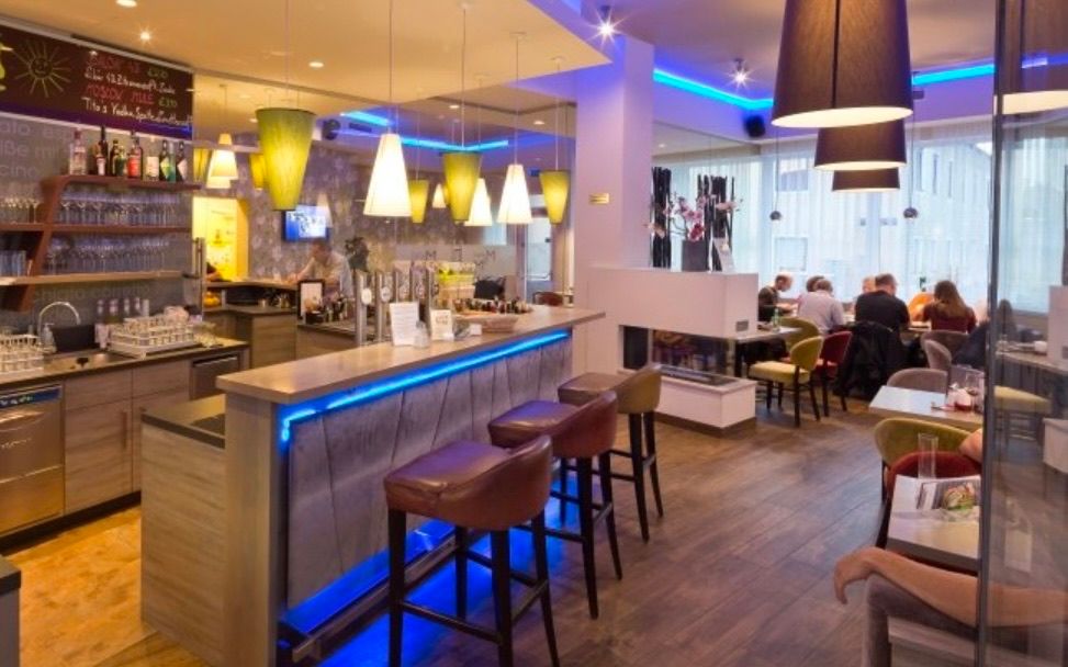 Bild enthält, Bar, Person, Architecture, Building, Indoors, Chair, Furniture, Restaurant, Monitor, Screen