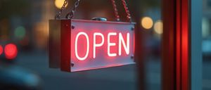 Ein Neonschild mit dem Wort offen hängt an einer Tür. Es ist mit rotem Licht beleuchtet.