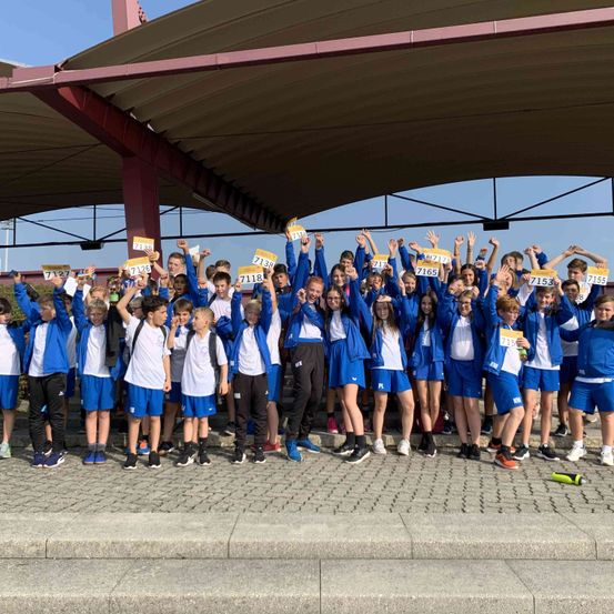 Eine Gruppe junger Schüler in blauen Uniformen hält gelbe Zahlen und posiert für ein Foto.