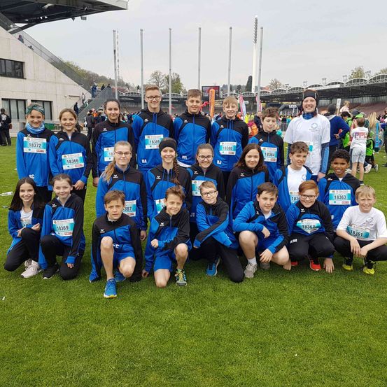 Eine Gruppe junger Athleten in blauen und schwarzen Uniformen posiert für ein Foto in einem Freiluftsportstadion.