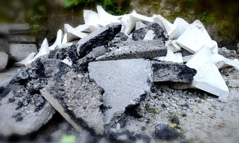 Ein Haufen zerbrochener Beton- und Steinstücke auf dem Boden, mit einigen weißen Stücken, die unter dem Schutt verstreut sind.