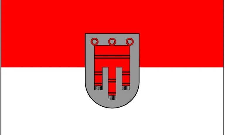 Die Flagge zeigt einen roten und weißen horizontalen Streifen mit einem grauen Schild in der Mitte. Der Schild hat ein rotes und graues Design.
