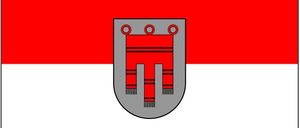 Die Flagge zeigt einen roten und weißen horizontalen Streifen mit einem grauen Schild in der Mitte. Der Schild hat ein rotes und graues Design.