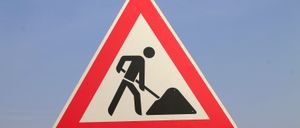 A triangular road sign with a man digging a hole, indicating roadwork ahead.