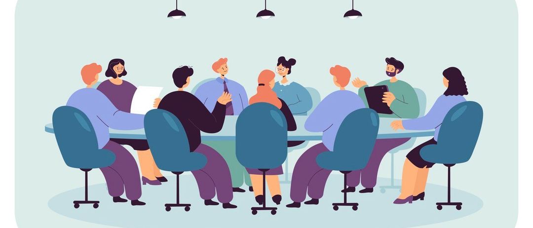 Eine Gruppe von Menschen sitzt in einem Besprechungsraum, möglicherweise auf einer Konferenz. Sie schauen den Mann auf der rechten Seite an, der ein Tablet hält. Einige von ihnen schauen auf die Papiere auf dem Tisch. Der Raum hat eine hellblaue Wand und eine Decke mit hängenden Lampen.