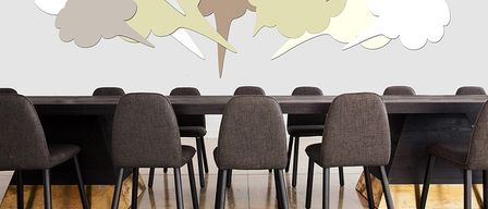 Ein Konferenzraum mit einem langen Tisch und Stühlen. Die Wand zeigt Sprechblasen-Designs in verschiedenen Farben.