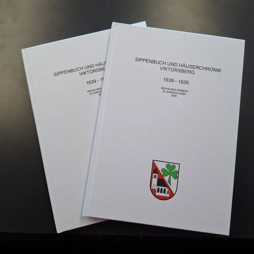 Zwei weiße Bücher mit dem Titel 'Sippenbuch und Hauserchronik Viktorsberg' mit den Daten 1639-1926 und 1639-1926. Beide Bücher haben ein Logo mit einem Kleeblatt in der Mitte.