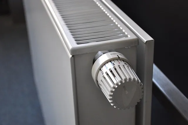 Ein Nahaufnahme einer weißen Heizung mit einem silbernen Thermostatknopf.