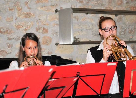Zwei Mädchen mit Brille spielen Trompeten mit Notenständern vor ihnen.