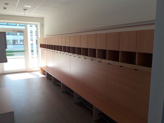 Ein leerer Raum mit Holzschränken und Regalen, einer Glastür und einem sonnigen Außenbereich.