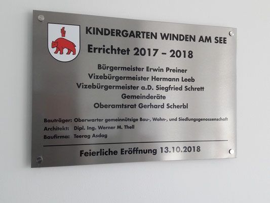 Eine Plakette für den Kindergarten Winden am See, errichtet 2017-2018. Sie listet Offizielle auf, darunter Bürgermeister Erwin Preiner, Vizebürgermeister Hermann Leeb und andere. Der Architekt ist Dipl. Ing. Werner M. Thell. Die feierliche Eröffnung war am 13.10.2018.
