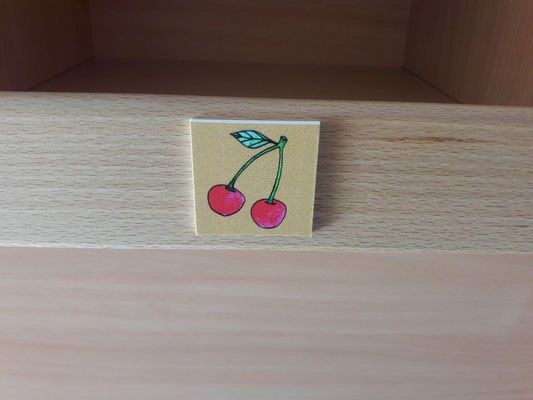Eine Holzschublade mit einem kleinen Aufkleber mit zwei Kirschen darauf.
