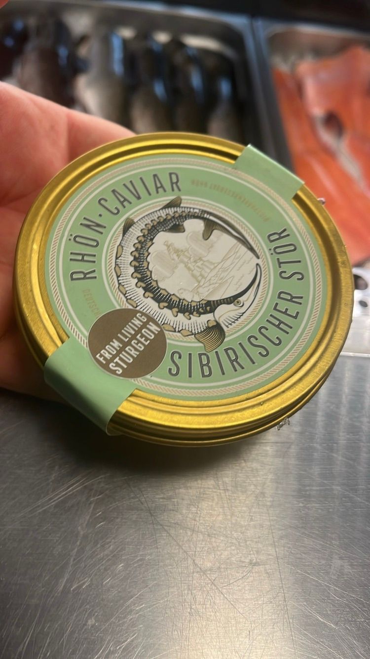 Ein goldenes Glas Kaviar von lebenden Stören. Das Etikett zeigt eine Illustration eines Fisches.