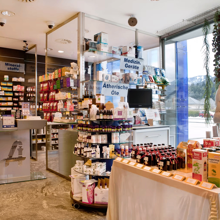 Eine Apotheke mit einer Vielzahl von Produkten, darunter Mineralstoffe und medizinische Geräte, die in Vitrinen ausgestellt sind. Der Laden verfügt auch über eine Glasvitrine und einen Monitor. Es gibt Überwachungskameras an der Decke.