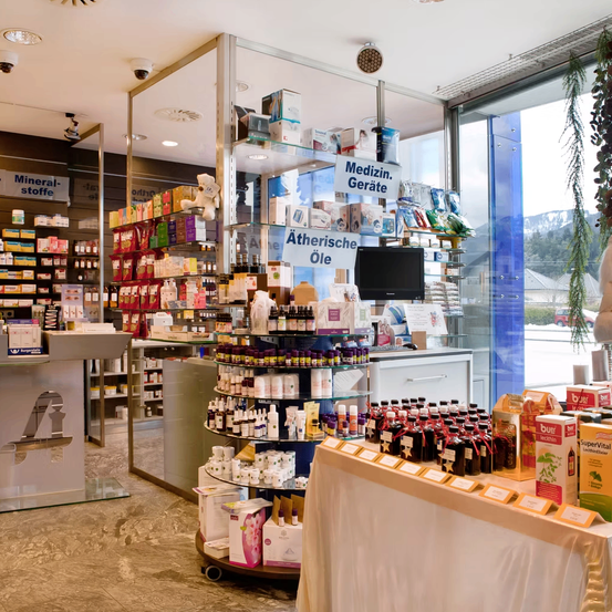 Eine Apotheke mit einer Vielzahl von Produkten, darunter Mineralstoffe und medizinische Geräte, die in Vitrinen ausgestellt sind. Der Laden verfügt auch über eine Glasvitrine und einen Monitor. Es gibt Überwachungskameras an der Decke.