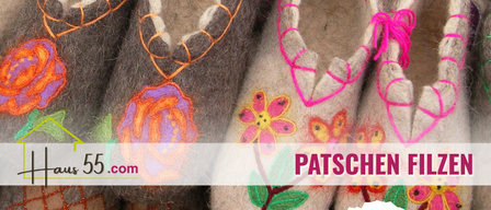 Ein Bild von vier Wollschläppchen mit Blumen- und Herzstickerei. Die Schläppchen haben rosa Schnürsenkel und sind in einer Reihe angeordnet. Der Text 'Patschen.com' ist im unteren linken Eck sichtbar.