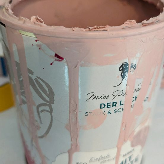 Ein teilweise gefüllter Behälter mit rosafarbener Farbe der Marke 'Miss Potts' und einer Silhouette eines Mädchens. Der Behälter ist geöffnet und zeigt den Inhalt.