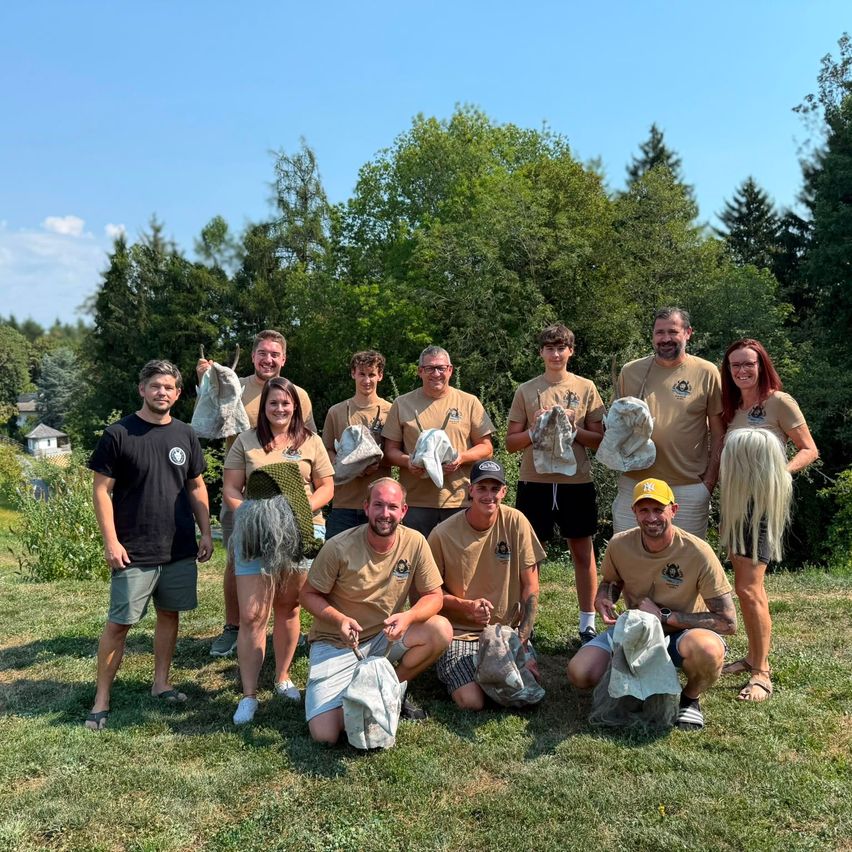Gruppe mit Künstlern hält handgefertigte Figuren auf einer grünen Wiese im Sommer.